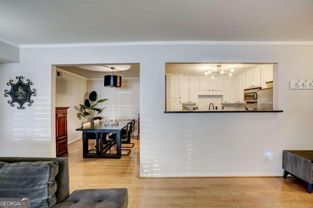 living room featuring light hardwood / wood-style flooring, a notable chandelier, crown molding, and sink