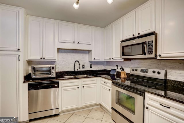 kitchen featuring white cabinets, appliances with stainless steel finishes, light tile patterned floors, and sink