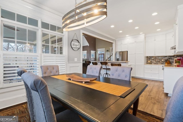 dining area featuring wood-type flooring, crown molding, and an inviting chandelier