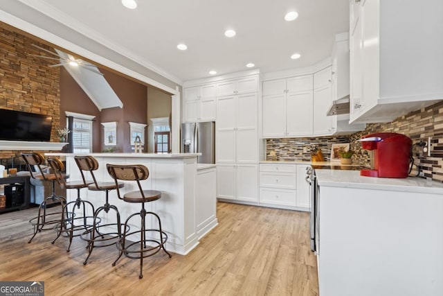 kitchen featuring a center island, stainless steel refrigerator with ice dispenser, a kitchen bar, white cabinets, and light wood-type flooring