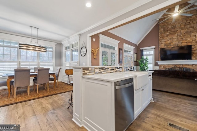 kitchen with white cabinetry, a healthy amount of sunlight, stainless steel dishwasher, and decorative light fixtures