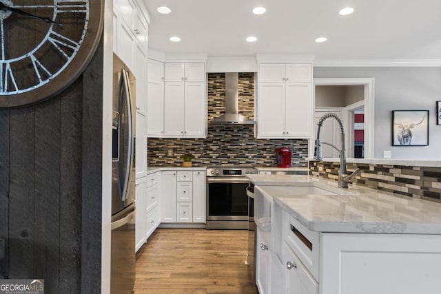 kitchen featuring light stone countertops, appliances with stainless steel finishes, wall chimney exhaust hood, light hardwood / wood-style floors, and white cabinetry