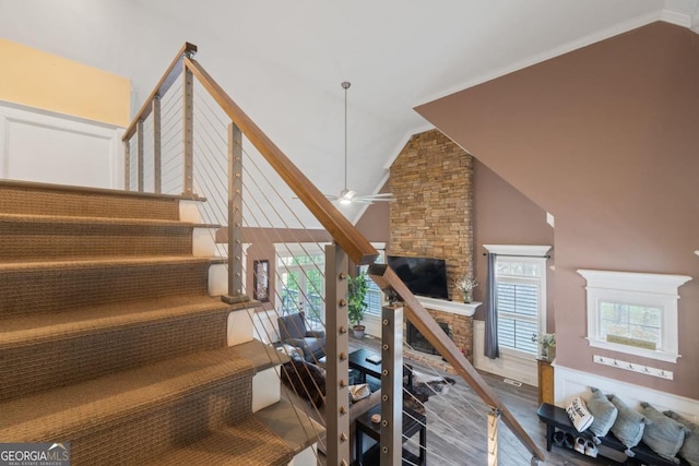 stairs featuring hardwood / wood-style floors, lofted ceiling, ceiling fan, and a healthy amount of sunlight