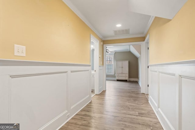 corridor featuring light hardwood / wood-style flooring, lofted ceiling, and ornamental molding