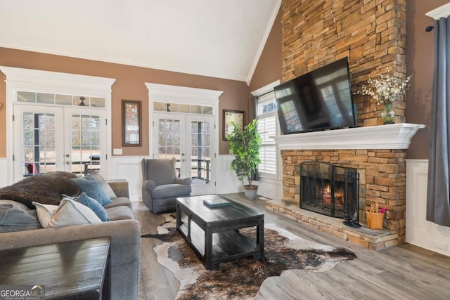 living room featuring hardwood / wood-style flooring, ornamental molding, a fireplace, and french doors