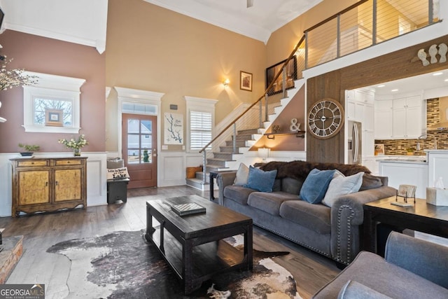 living room featuring crown molding, a towering ceiling, and dark wood-type flooring