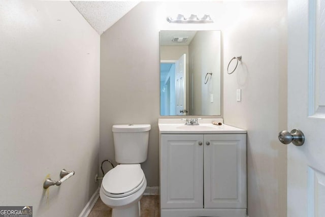 bathroom featuring a textured ceiling, vanity, lofted ceiling, and toilet