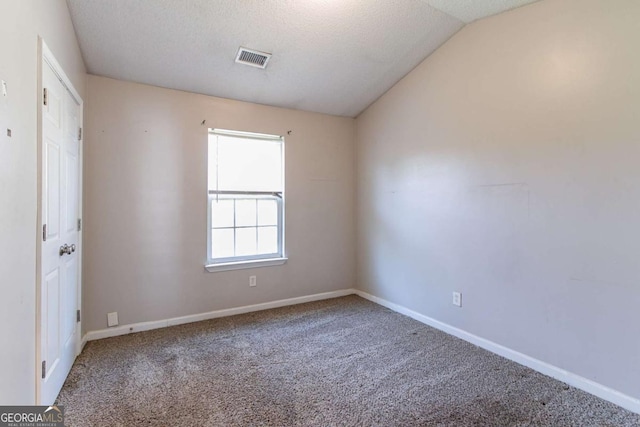 carpeted spare room with a textured ceiling and vaulted ceiling