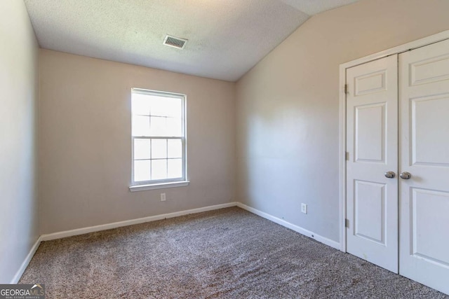 carpeted spare room featuring lofted ceiling and a textured ceiling