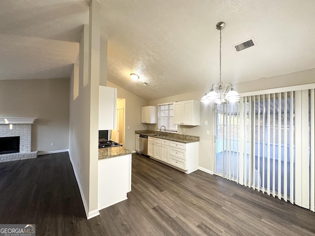 kitchen featuring stainless steel appliances, vaulted ceiling, decorative light fixtures, dark hardwood / wood-style floors, and white cabinetry