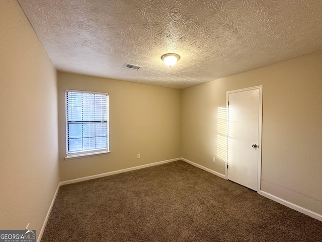 unfurnished room with dark colored carpet and a textured ceiling