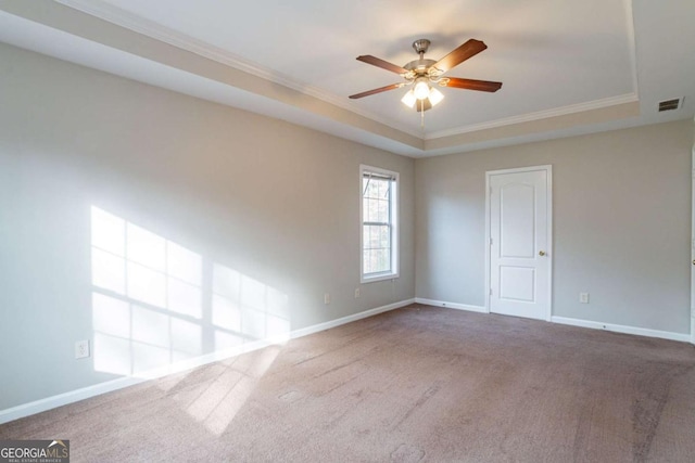 carpeted empty room with a tray ceiling, ceiling fan, and ornamental molding