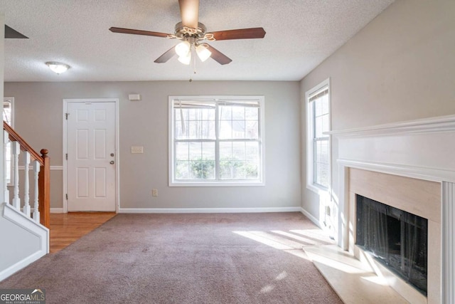 unfurnished living room with ceiling fan, light colored carpet, and a textured ceiling