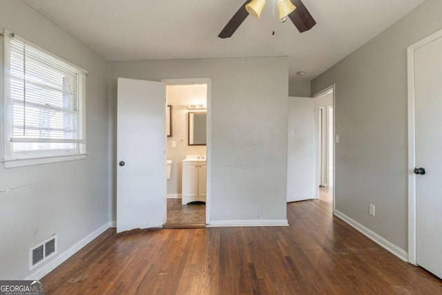 unfurnished bedroom featuring dark hardwood / wood-style floors, ceiling fan, and connected bathroom