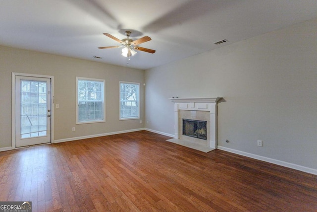 unfurnished living room with ceiling fan, a fireplace, and wood-type flooring