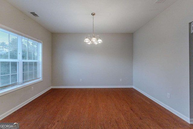 unfurnished room featuring a chandelier and dark wood-type flooring