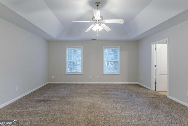 spare room featuring ceiling fan, a raised ceiling, and light colored carpet