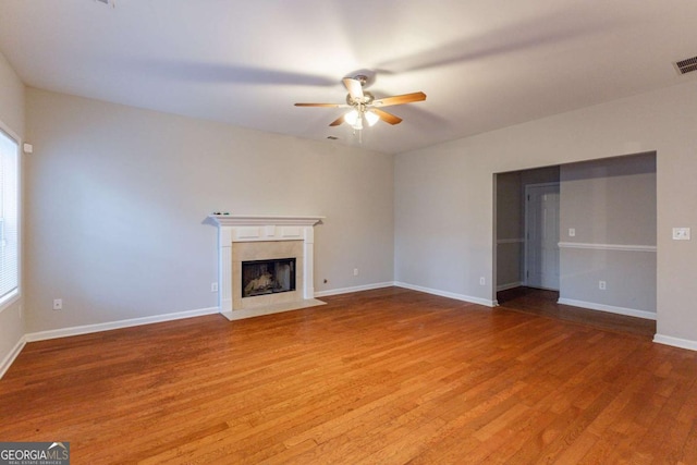 unfurnished living room featuring ceiling fan, hardwood / wood-style floors, and a premium fireplace