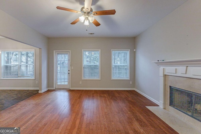 unfurnished living room with hardwood / wood-style floors, ceiling fan, and a premium fireplace