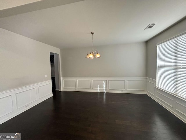 unfurnished room featuring dark wood-type flooring and a notable chandelier