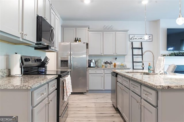 kitchen featuring light stone counters, gray cabinetry, stainless steel appliances, sink, and decorative light fixtures