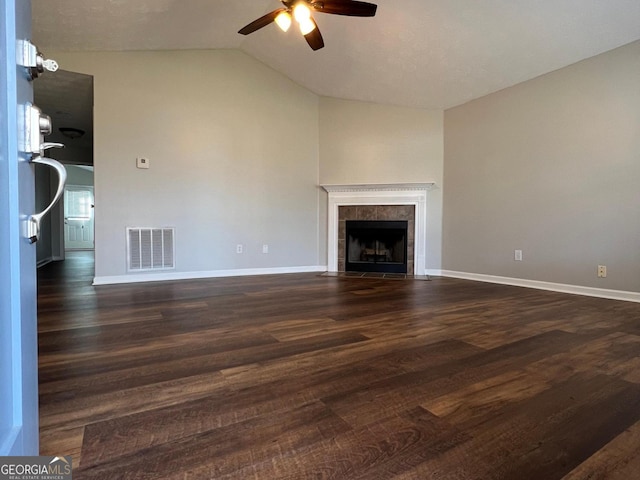 unfurnished living room featuring ceiling fan, dark wood-type flooring, a tile fireplace, and vaulted ceiling