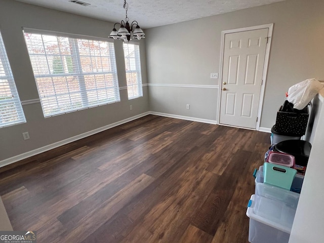 dining area featuring a notable chandelier, dark hardwood / wood-style floors, and a textured ceiling