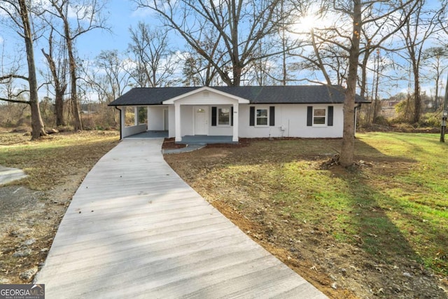 ranch-style house featuring covered porch, a carport, and a front yard