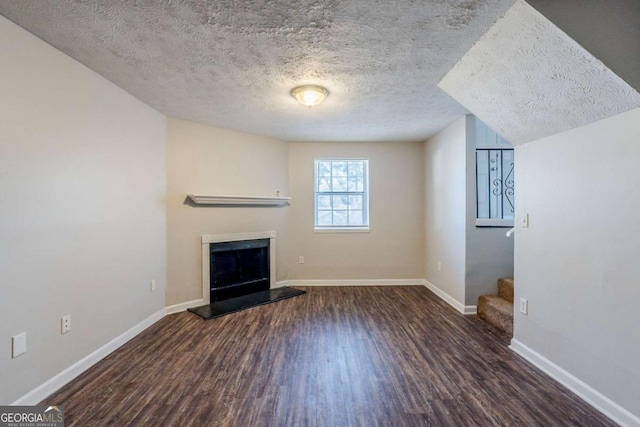 unfurnished living room with a textured ceiling, dark hardwood / wood-style floors, and lofted ceiling