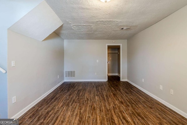 bonus room with a textured ceiling and dark wood-type flooring