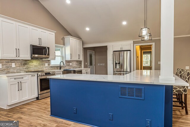 3625 Pointer Rd, Loganville, GA 30052 - kitchen featuring stainless steel appliances, decorative backsplash, a breakfast bar, white cabinets, and light wood-style floors