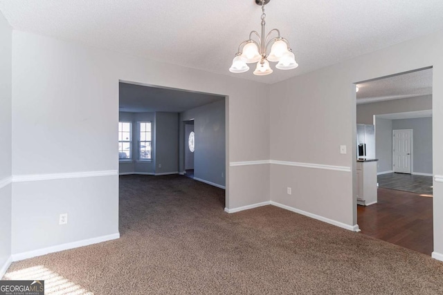 carpeted spare room with a chandelier and a textured ceiling