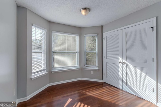 unfurnished bedroom with dark hardwood / wood-style flooring and a textured ceiling