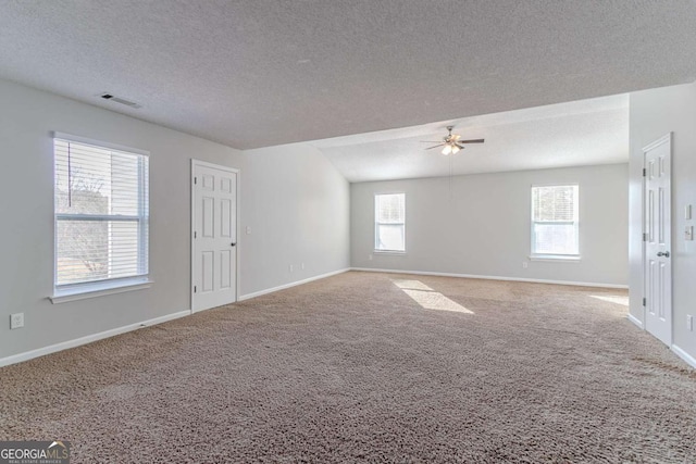 carpeted empty room featuring a textured ceiling, a wealth of natural light, and ceiling fan