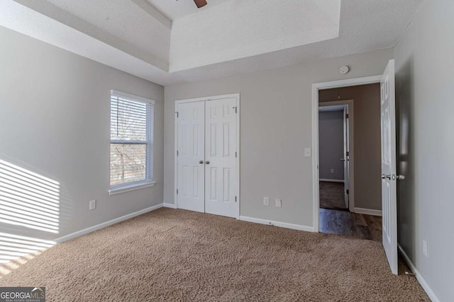 unfurnished bedroom with a textured ceiling, carpet floors, a closet, and ceiling fan