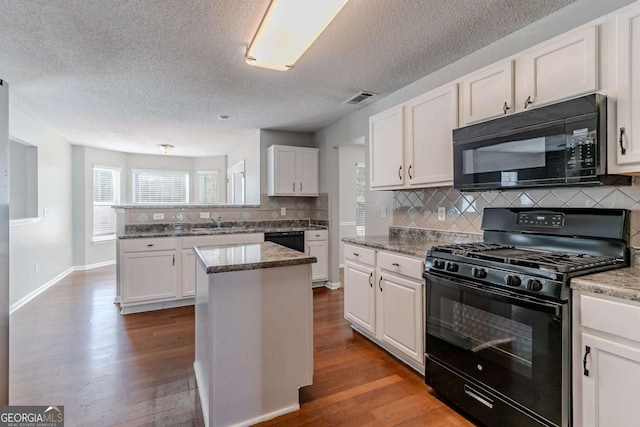 kitchen with white cabinetry, a center island, black appliances, and hardwood / wood-style flooring