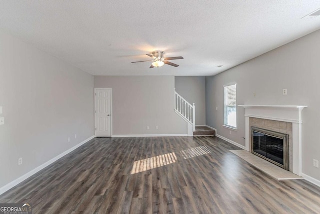 unfurnished living room featuring a textured ceiling, ceiling fan, dark hardwood / wood-style flooring, and a fireplace