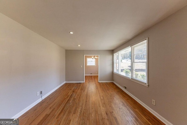 spare room featuring light hardwood / wood-style floors and an inviting chandelier