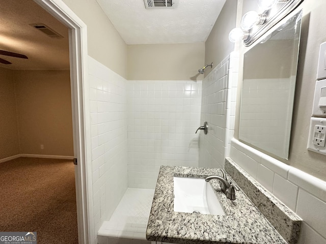 bathroom with vanity, a textured ceiling, and tiled shower