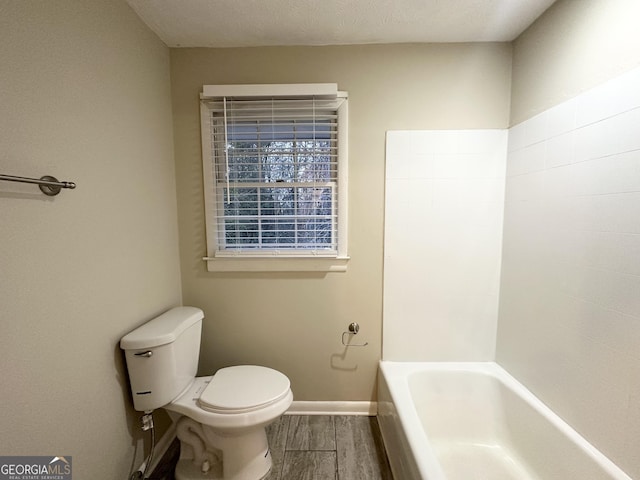 bathroom with a bath, a textured ceiling, hardwood / wood-style flooring, and toilet