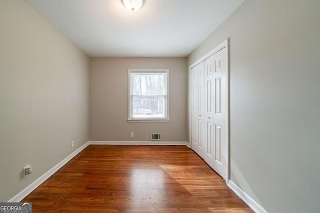 unfurnished bedroom with wood-type flooring and a closet