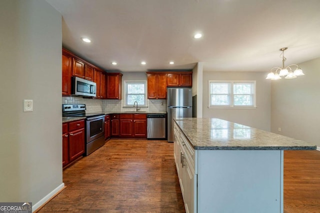 kitchen featuring tasteful backsplash, light stone counters, stainless steel appliances, a notable chandelier, and dark hardwood / wood-style floors