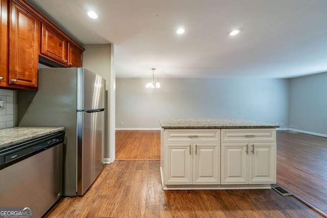 kitchen featuring pendant lighting, dishwasher, an inviting chandelier, hardwood / wood-style flooring, and light stone countertops