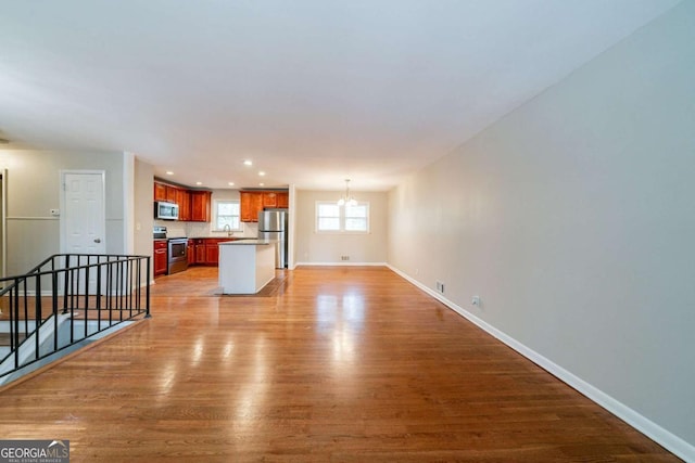 unfurnished living room with sink, light hardwood / wood-style flooring, and a notable chandelier