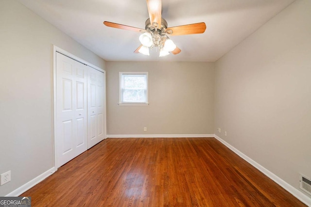 unfurnished bedroom featuring ceiling fan, dark hardwood / wood-style flooring, and a closet