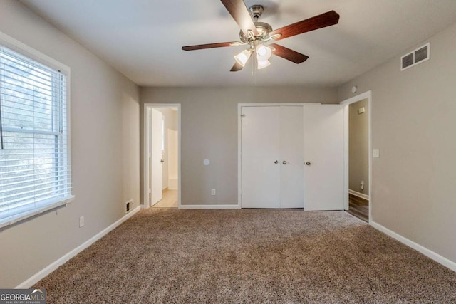 unfurnished bedroom featuring connected bathroom, a closet, ceiling fan, and light colored carpet