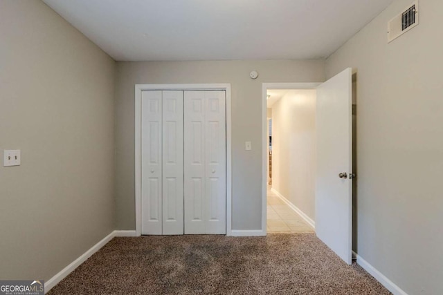 unfurnished bedroom featuring a closet and light colored carpet