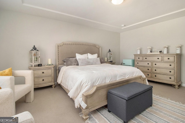 bedroom featuring a raised ceiling and light colored carpet