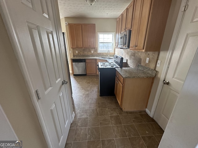 kitchen featuring sink, stainless steel appliances, tasteful backsplash, a textured ceiling, and dark tile patterned flooring