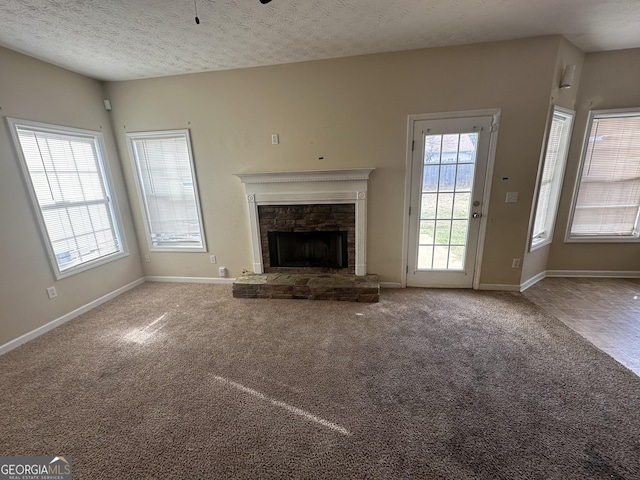 unfurnished living room featuring a textured ceiling, ceiling fan, carpet floors, and a fireplace